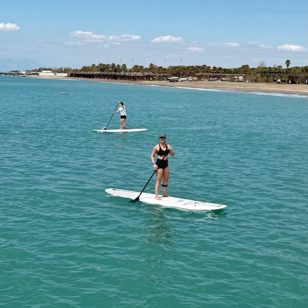 Açık denizde SUP tahtası üzerinde denge egzersizi yapan iki sporcu